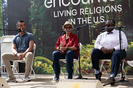 Three people seated on stage in front of microphones.