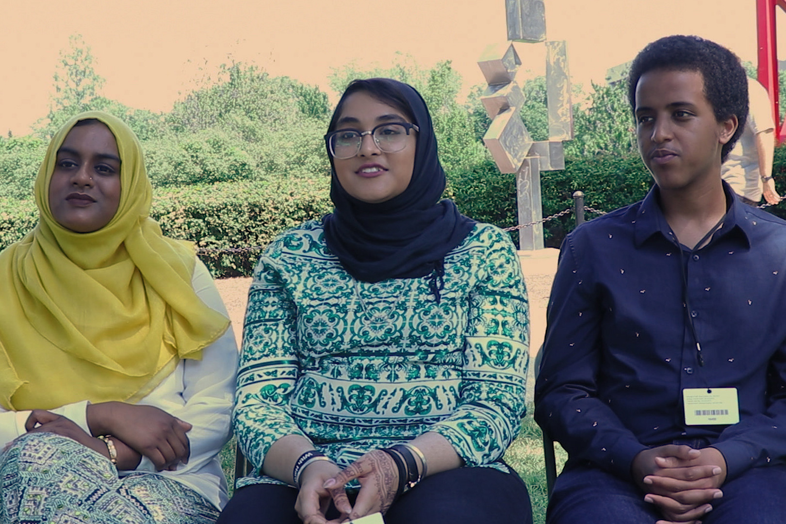 Three people, including two women in hijab, sit side by side for an interview.
