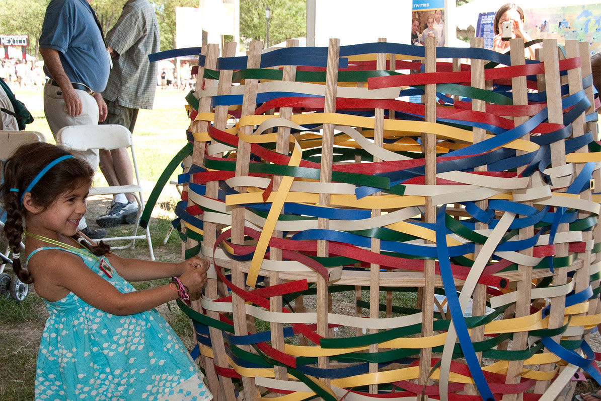 A young girl pulls strands on an oversized, multicolor basket.