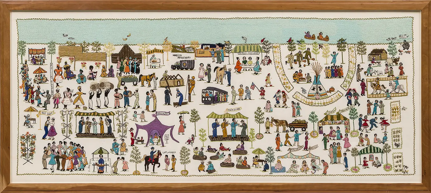 A wooden-framed, horizontal, rectangular cloth of detailed embroidery depicts detailed colorful scenes of people dancing, crafting, playing music, feeding animals, and other activities. 