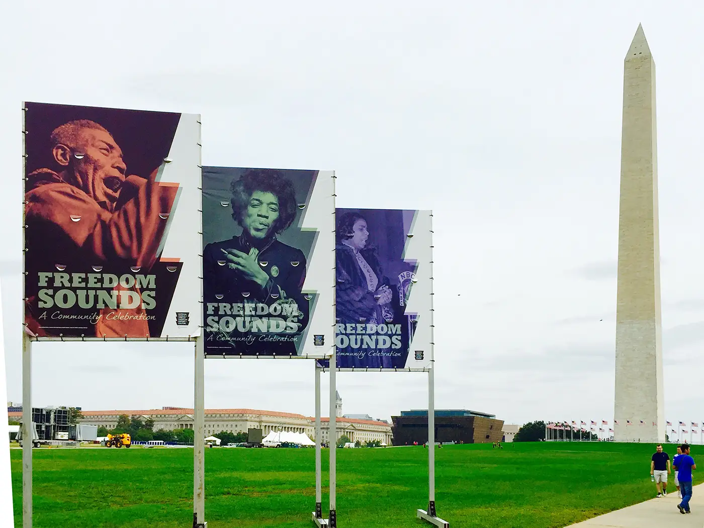 Three large event banners with the words “Freedom Sounds, A Community Celebration” on the National Mall, with a museum and the Washington Monument in the background. 