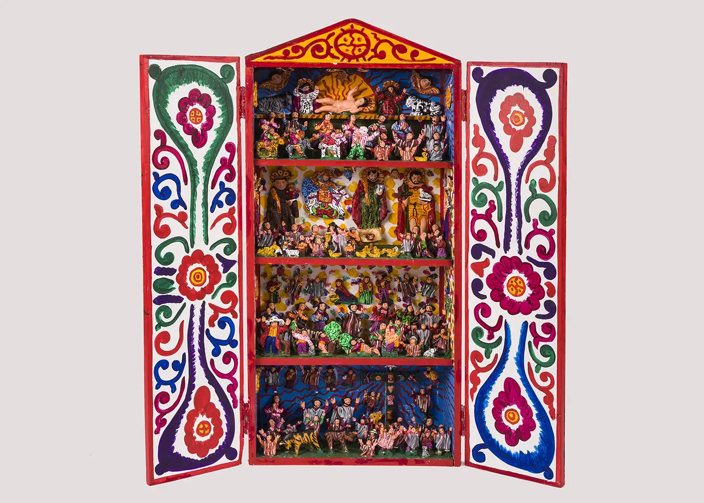 A tall wooden cabinet, with doors wide open, features brightly colored, detailed scenes created from numerous clay figurines arranged on four shelves.   