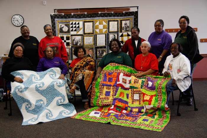 Maxine Stovall and Kathy Muhammad holding an African American history themed quilt made by a member of the Sisters of the Cloth Quilting Guild in Fort Wayne, Indiana. Photo by Jon Kay