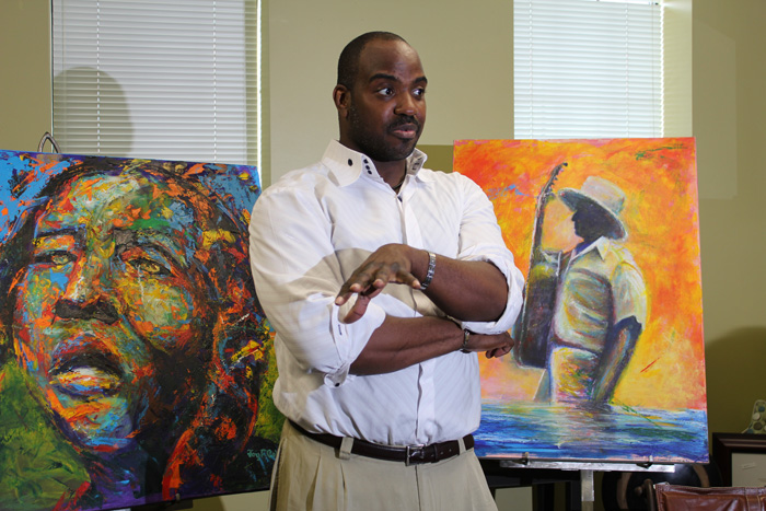 Jay Coleman with two of his portraits at Adobe Design Center and Showroom.