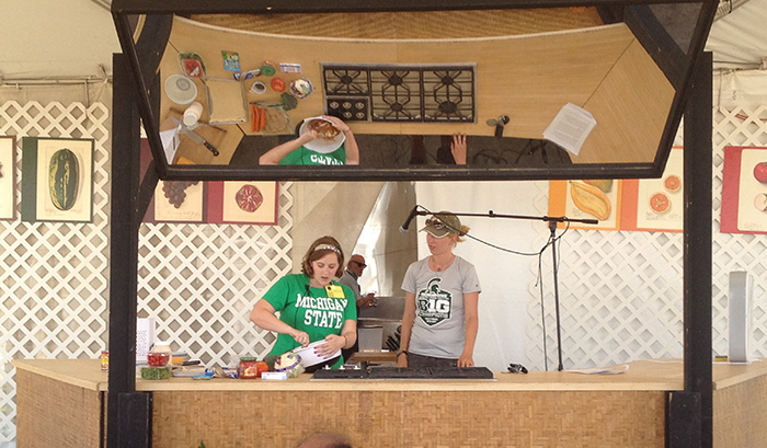 Meghan Burke (left) and Emily Langenberg (right), two recent Michigan State University graduates, demonstrate some cheesy cuisine recipes at the Test Kitchen of the 2012 Campus and Community program. Photo by Kurt Dewhurst