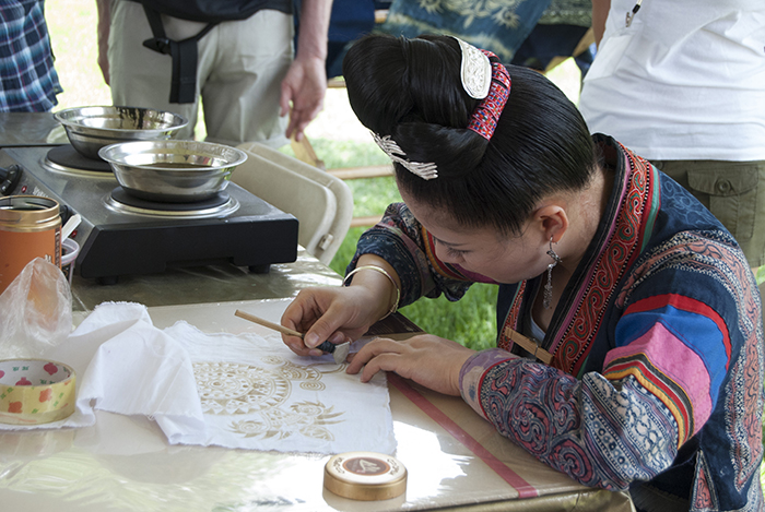 An artist from Guizhou Province applies wax for a batik print.