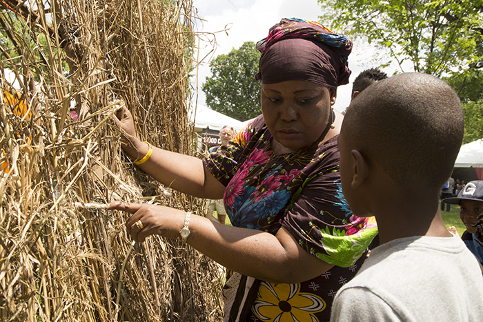 A Pokomo woman explains the thatched hut to a young visitor.