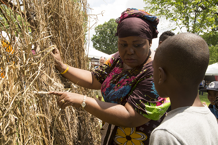 One of the Pokomo hut builders explains hr craft to a young Festival visitor.