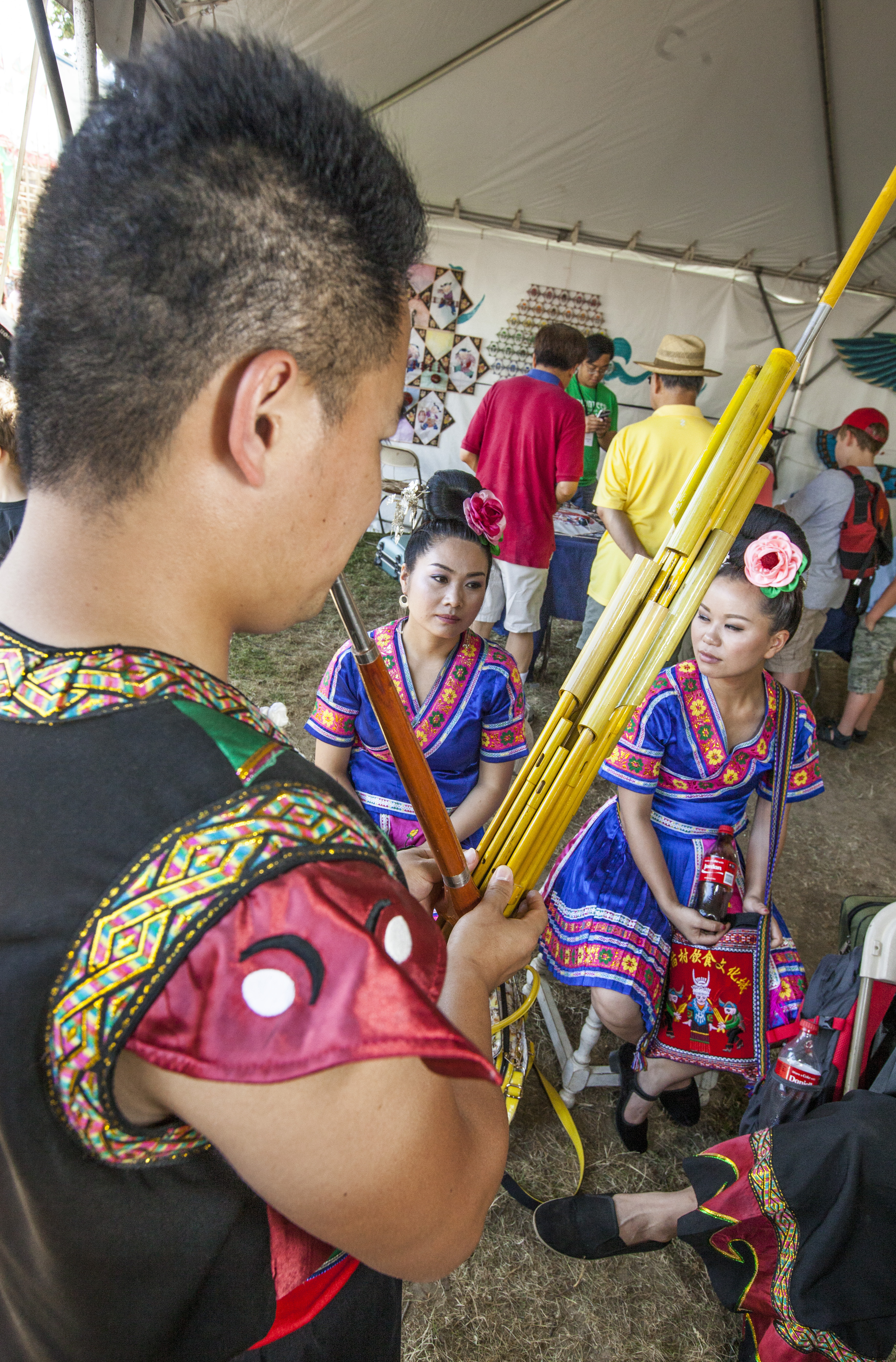 Mo Ming, a lusheng maker and player, plays a more modern lusheng while Miao dancers sit and listen.