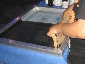 MONKY spreads paint across the screen to print a design. Photo by Georgia Dassler, Ralph Rinzler Folklife Archives