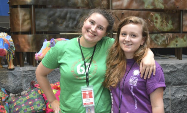 Interns Carly Blancato and Emma Tainter model some of the T-shirts for sale in the Festival Marketplace. Photo by Sarah Bluestein, Ralph Rinzler Folklife Archives