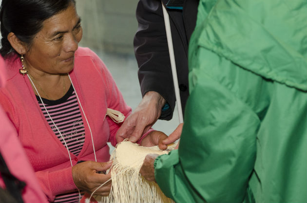 Hat weaver Margarita Guzmán lets a visitor feel her work. Photo by Josh Weilepp, Ralph Rinzler Folklife Archives