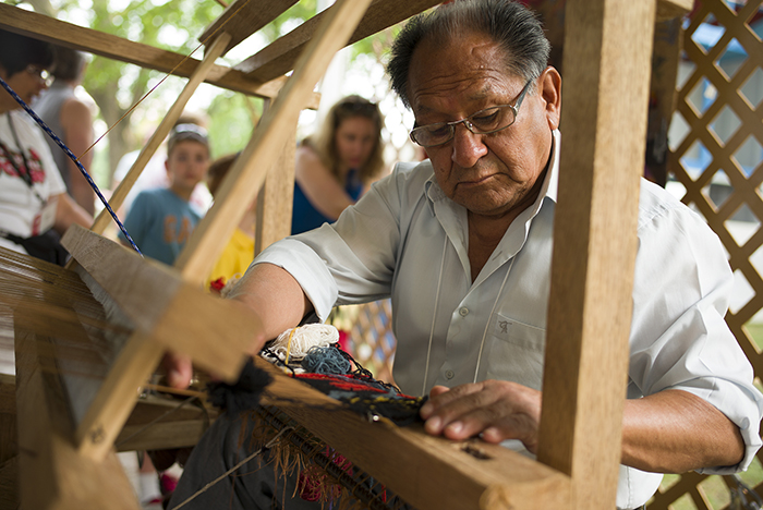 Alfonso Sulca quietly worked away on his boldly colored woven tapestries. Photo by Vivianne Peckham, Ralph Rinzler Folklife Archives