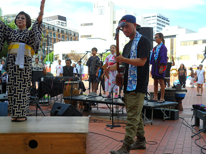 Elaine Fukumoto teaches a dance while standing on Quetzal’s tarima, the raised wooden platform used for percussive dancing. Sean Miura plays shamisen beside her. Photo by Deborah Wong