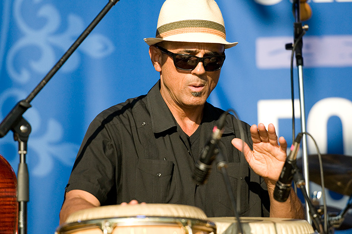 A man play conga drums with his hands on stage.